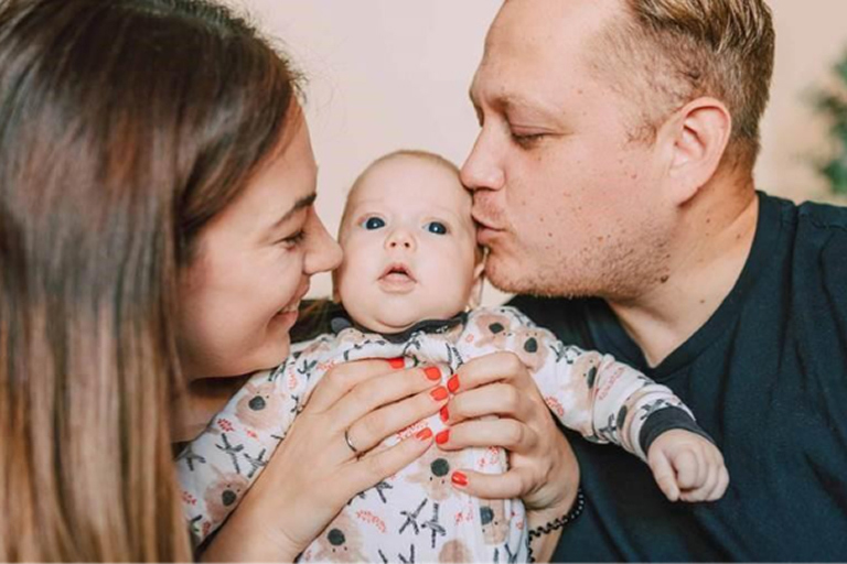 Parents kissing their newborn baby