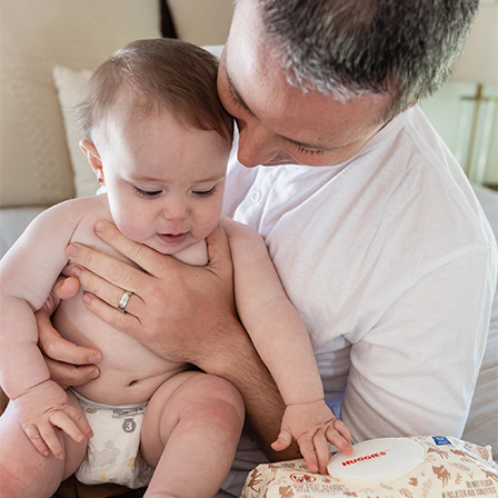 A father cuddling with a child with Huggies® Calm™ Baby Wipes in view