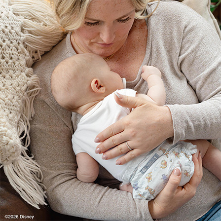 Mother cuddling with baby while baby wears Huggies® Little Snugglers® Plus diapers